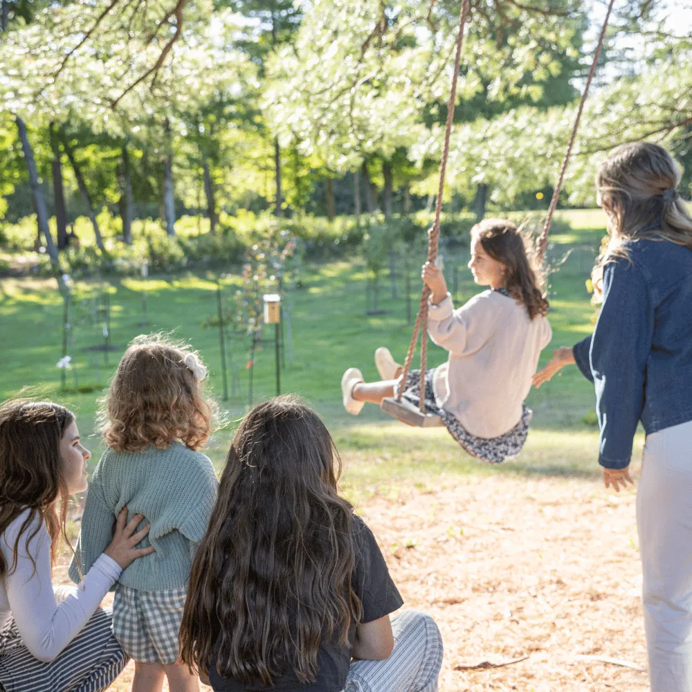 Des enfants regardent une balançoire sous les arbres